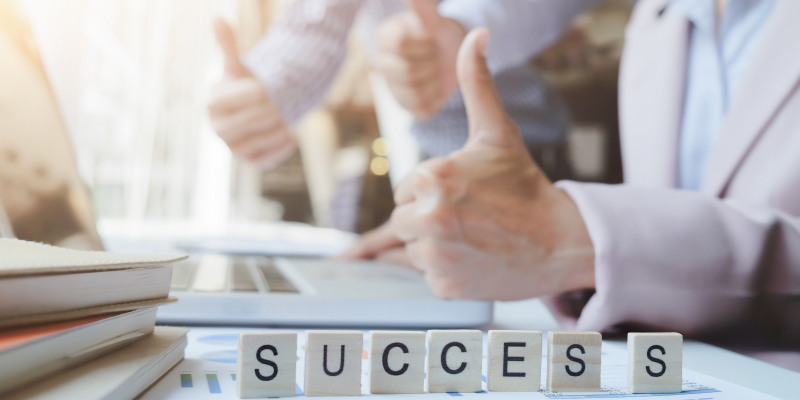 The word "Success" on wooden blocks are placed on the businessman’s work table.